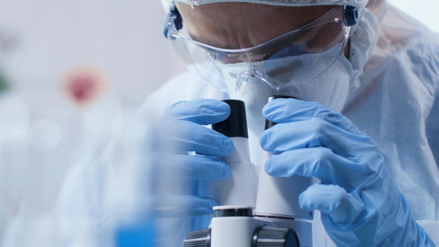 closeup of scientist doctor looking into medical microscope