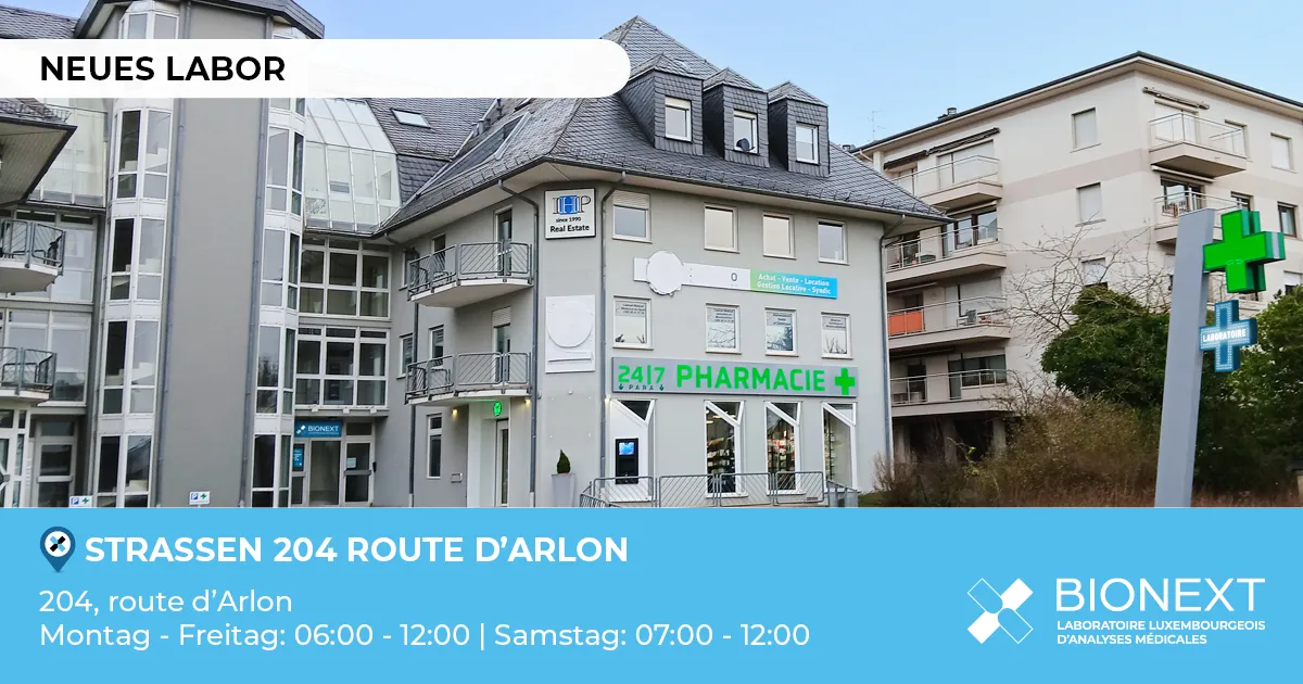 Fassade eines neuen BIONEXT-Labors in der 204, route d’Arlon in Strassen, neben einer Apotheke mit leuchtendem grünem Kreuz. Das Bild zeigt den Hinweis ‚Neues Labor‘ sowie die Öffnungszeiten: Montag bis Freitag von 06:00 bis 12:00 Uhr und Samstag von 07:00 bis 12:00 Uhr.
