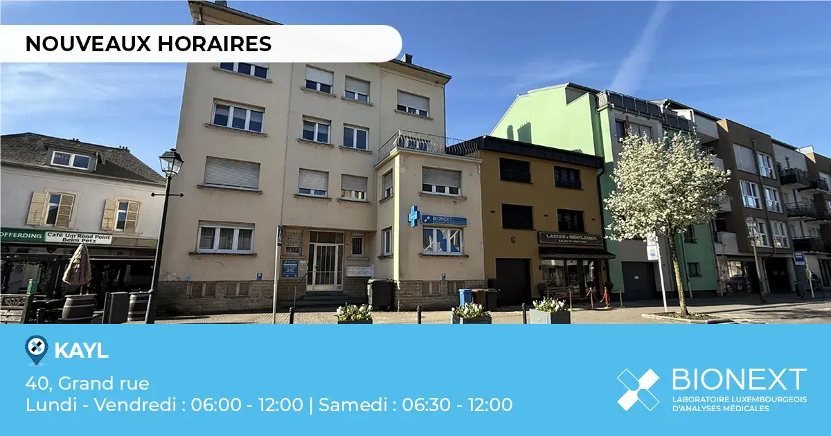 Façade d’un bâtiment BIONEXT situé à Kayl, avec la mention ‘Nouveaux horaires’. L’image indique l’adresse ‘40, Grand rue’ et les horaires d’ouverture : du lundi au vendredi de 06h00 à 12h00 et le samedi de 06h30 à 12h00.